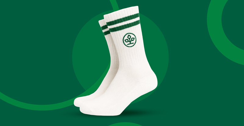 Ein Paar weiße Laufsocken mit zwei grünen Streifen und gesticktem AOK-Logo.